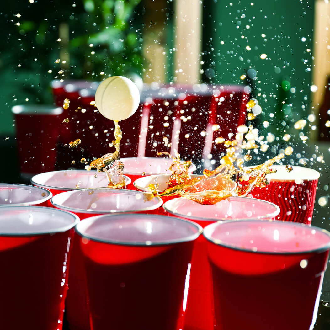 Beer Pong Becher werden getroffen und Bier spritzt
