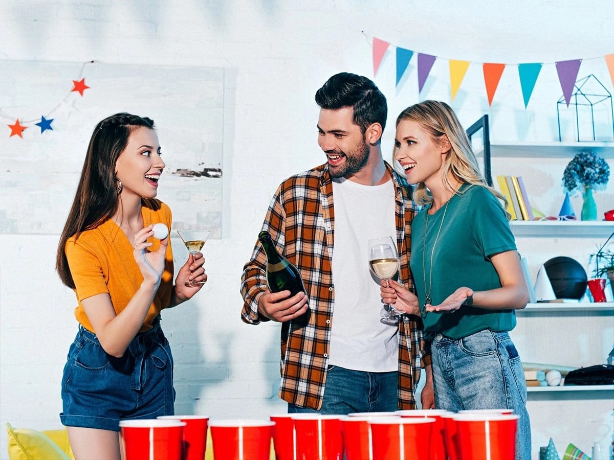 Ein Mann und zwei attraktive Frauen spielen Beerpong