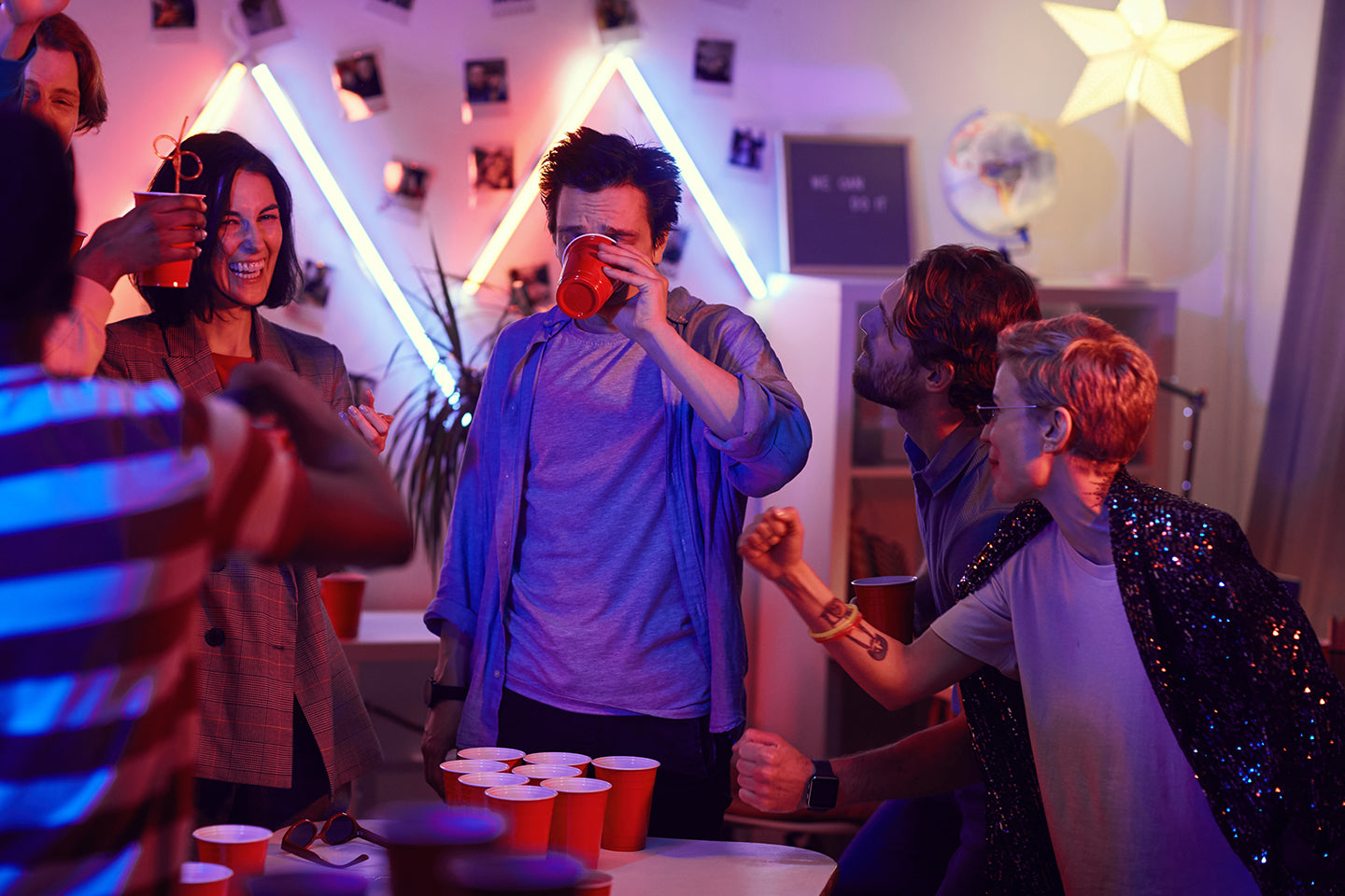 Spieler hat verloren und leert den Beer Pong Becher auf einer Party
