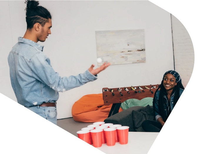 Mann und Frau spielen Bier Pong in der Wohnung